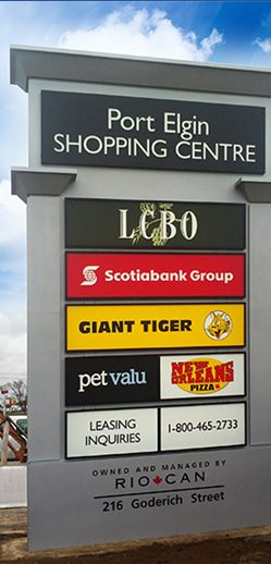 Illuminated pylon sign standing beside a parking lot entrance