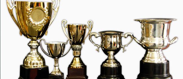 Gold sports trophies with figurine toppers on marble bases